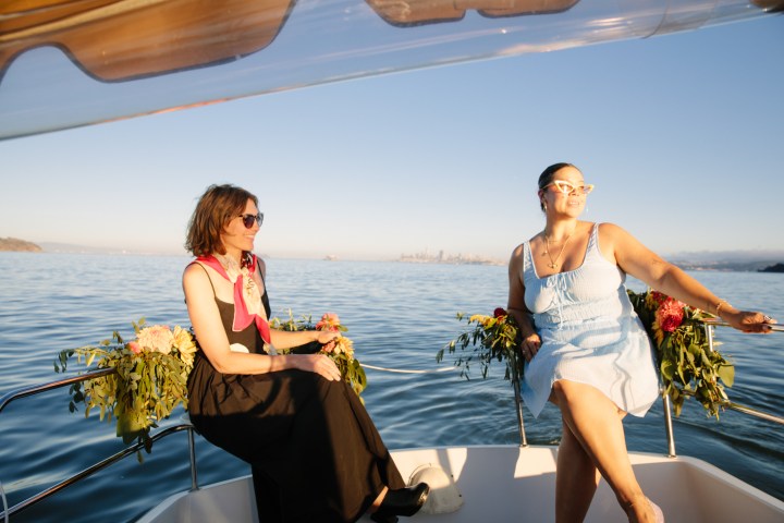 Two people sitting on a boat decorated with flowers, enjoying a sunny day.